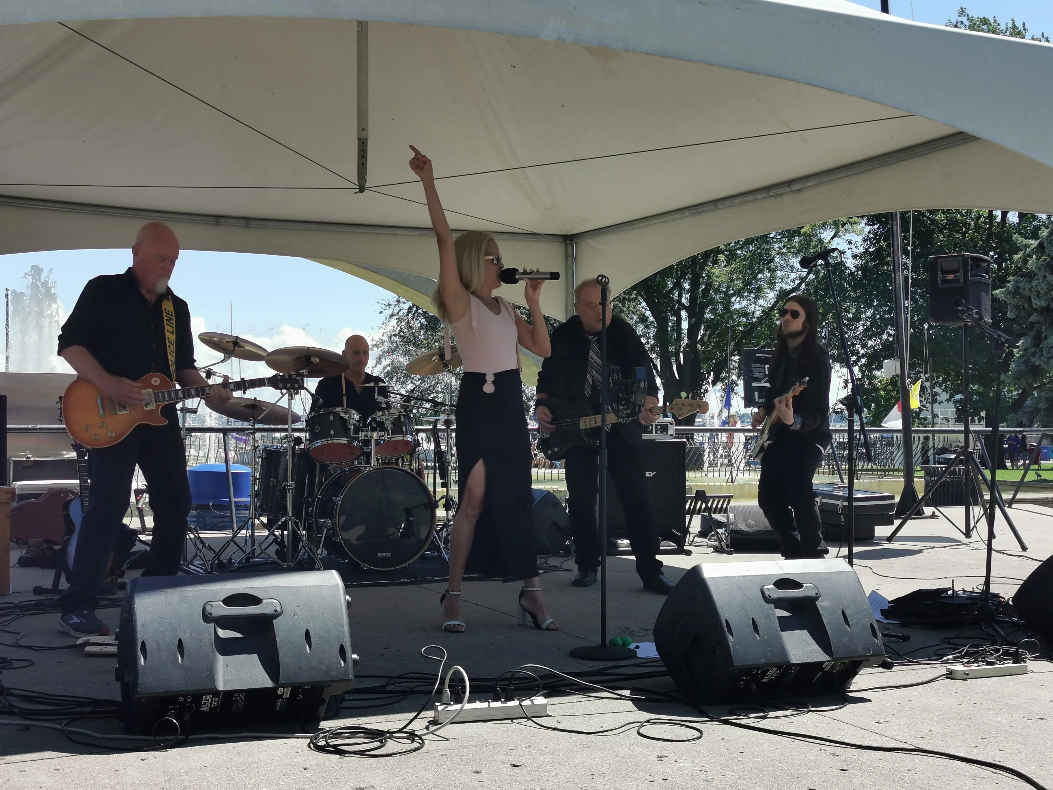 River Cats performing live at Confederation Basin downtown Kingston with city skyline backdrop and afternoon crowd